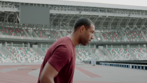 Retrato-De-Un-Hombre-Afroamericano-De-Raza-Negra-Calentándose-Antes-De-Correr-En-Una-Pista-De-Estadio-Vacía-Temprano-En-La-Mañana.-Toma-Tomada-Con-Lente-Anamórfica.